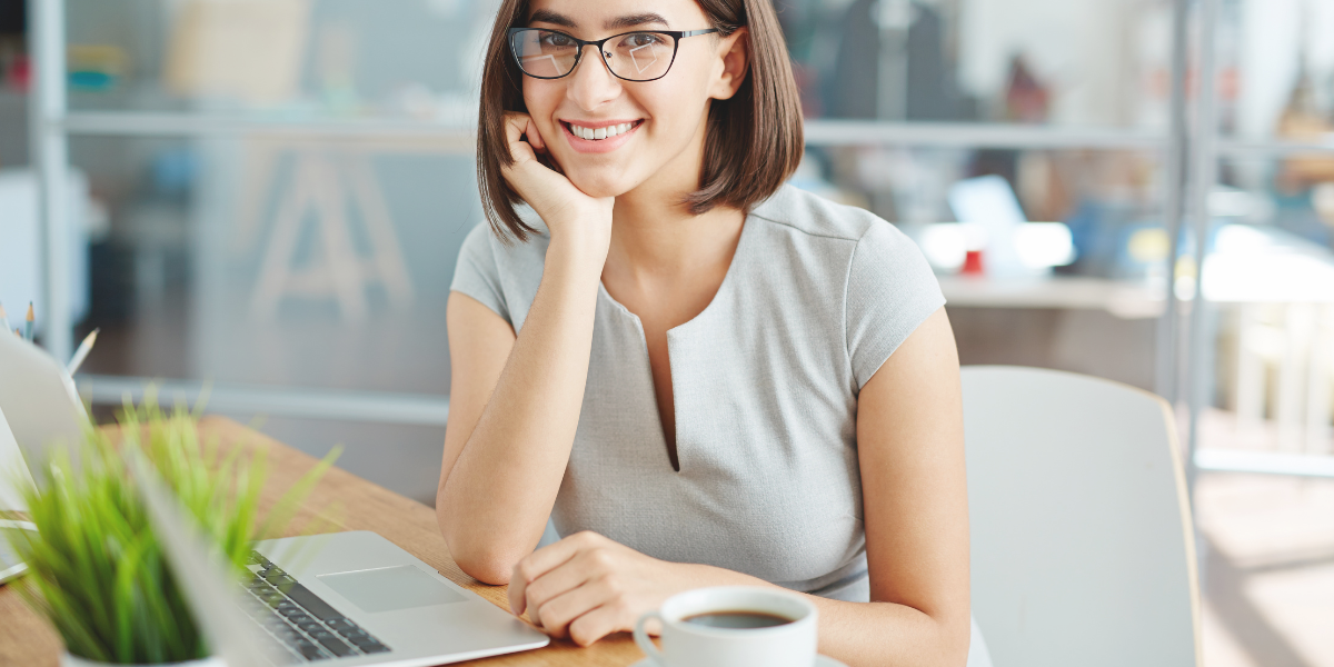 Personne travaillant sur un ordinateur portable dans un bureau moderne avec une tasse de café sur le bureau