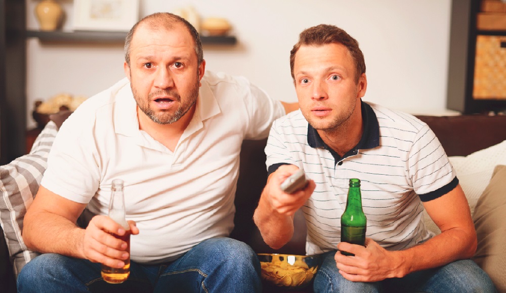 Sitting on couch holding beer with remote in hand